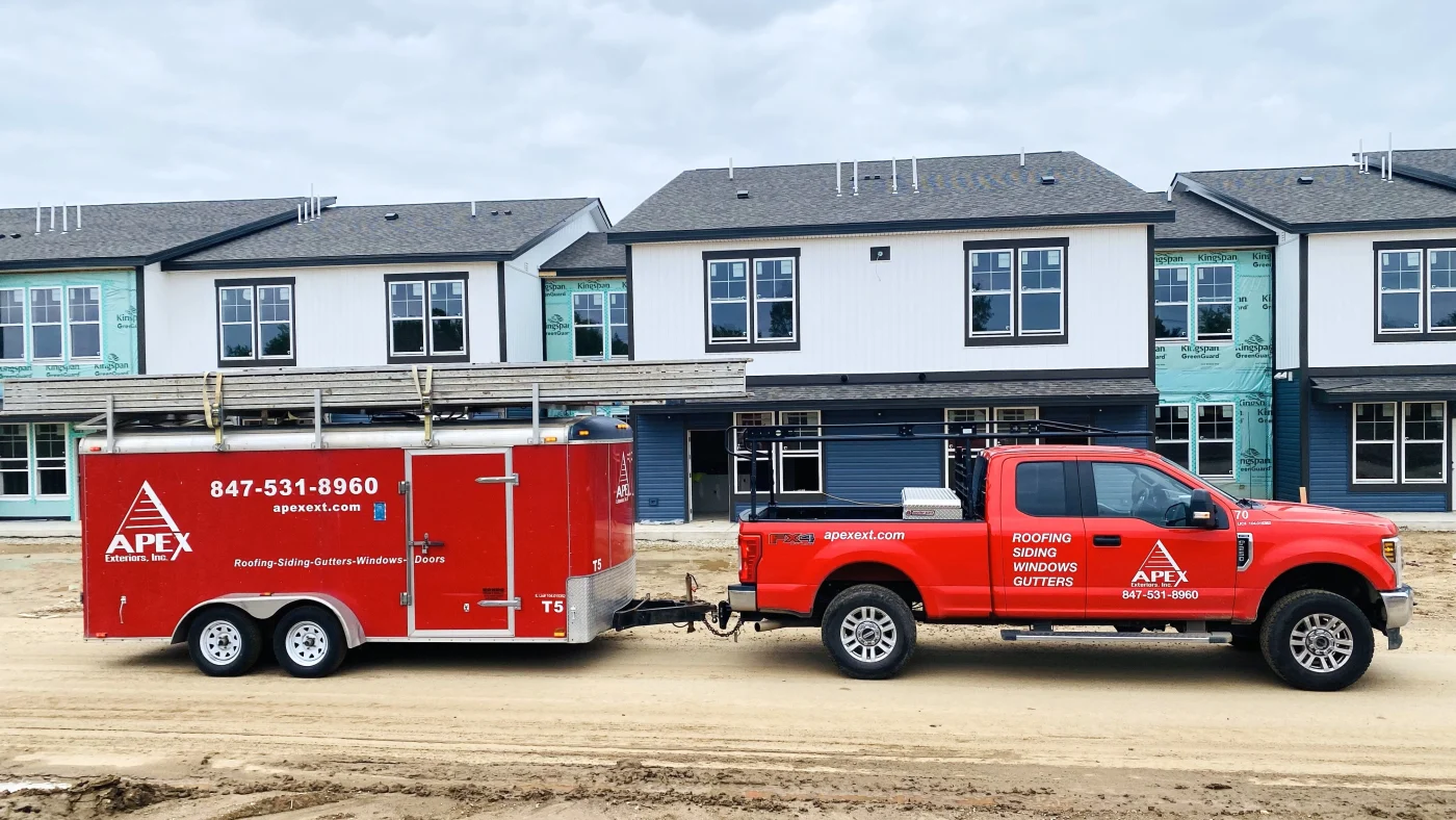 An Apex truck parked in front of apartment buildings under construction in Wheaton, IL by Apex Exteriors.