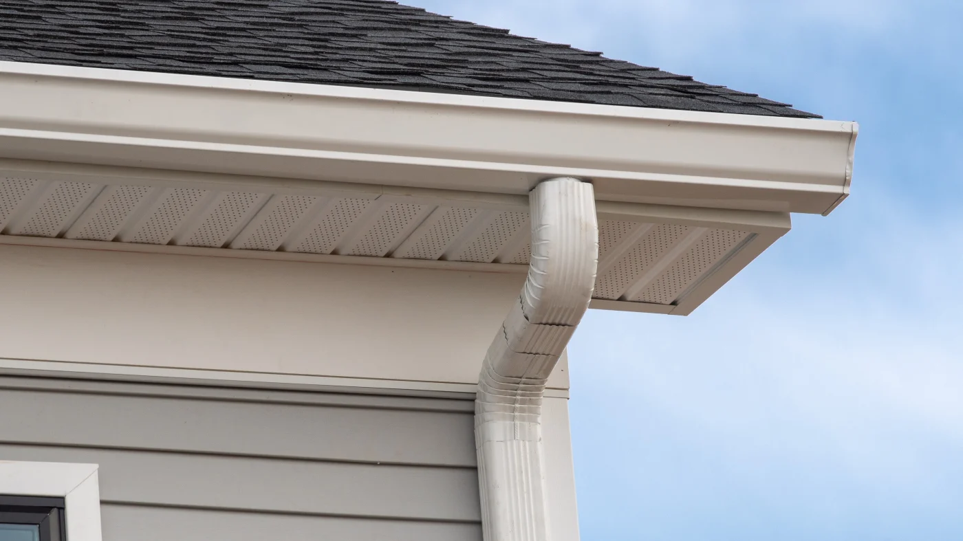 A close-up of white gutters on a house with a black roof in Bloomingdale, IL by Apex Exteriors.