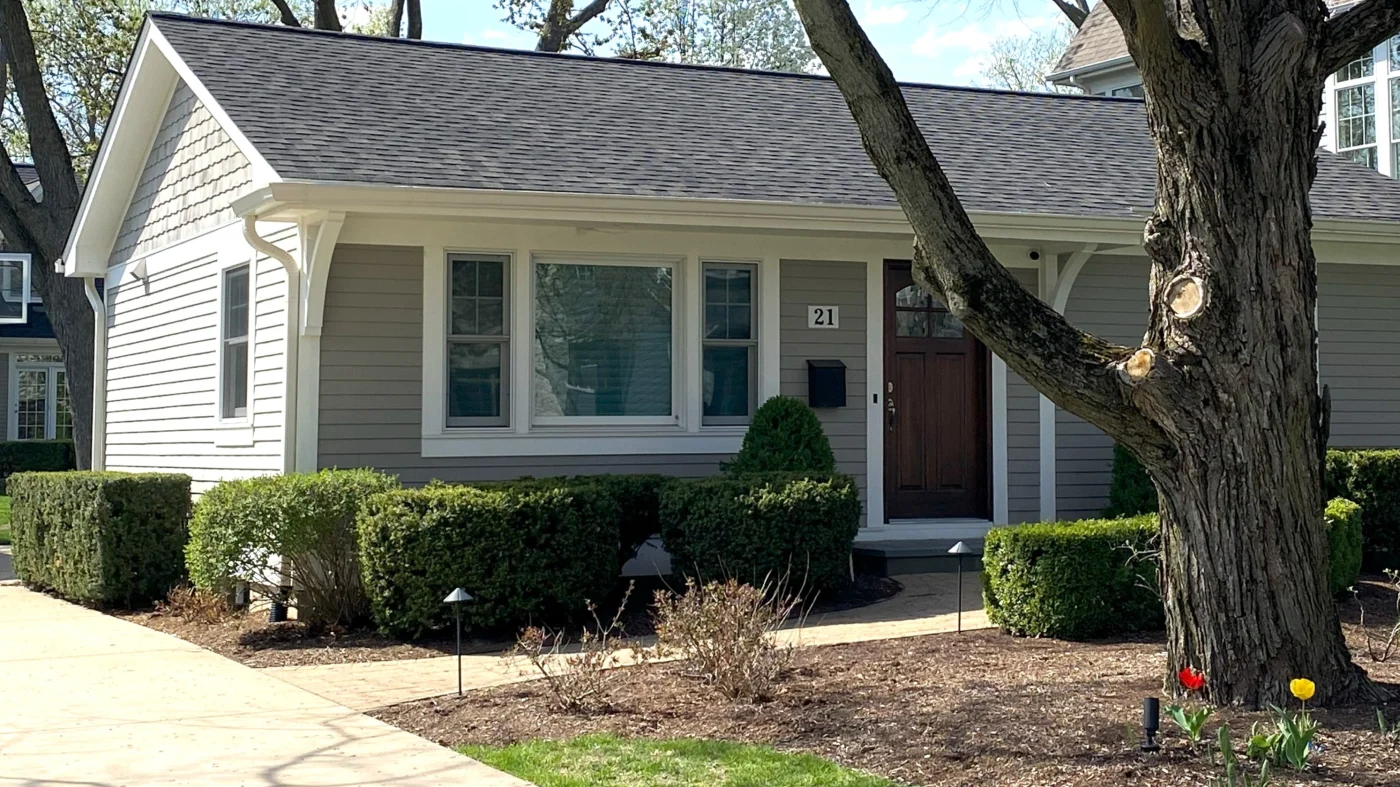 The front of a house with light gray siding and a brown entry door in Wheaton, IL by Apex Exteriors.