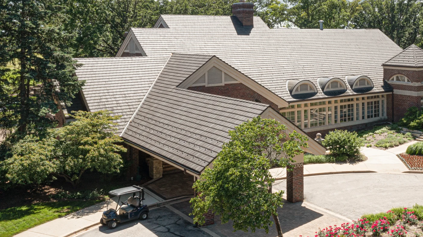 A drone view of a large commercial building with a brown roof in Wheaton, IL by Apex Exteriors.