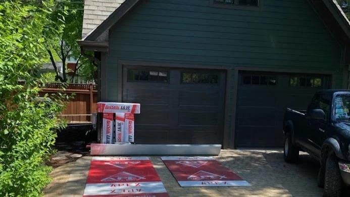 The front of a house with dark green siding and the two-car garage with brown garage doors in Bloomingdale, IL by Apex Exteriors.