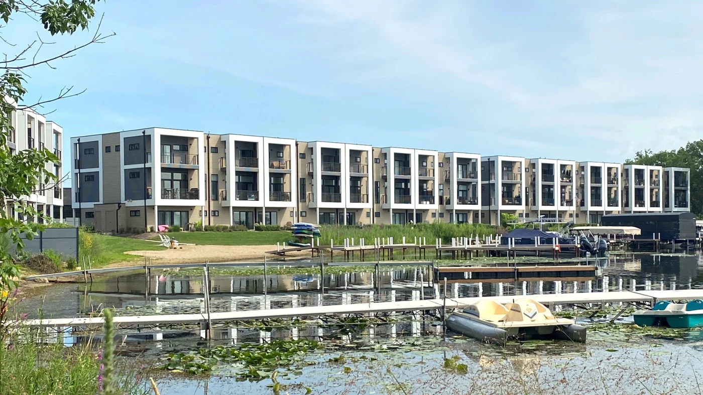 A view from across a pond of a row of connected multi-family housing units in Lombard, IL by Apex Exteriors.