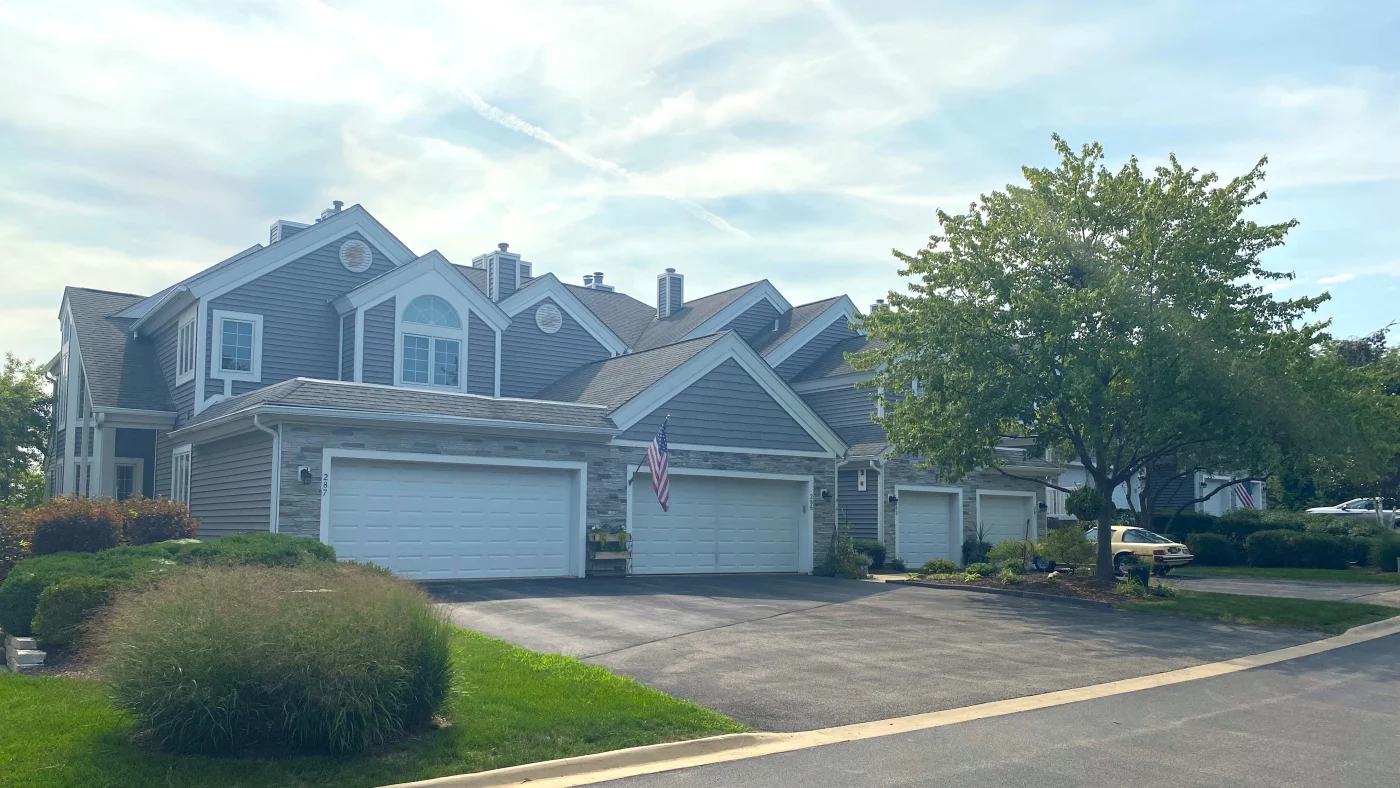 A large home with light brown siding and white trim on a street in LaGrange, IL by Apex Exteriors.