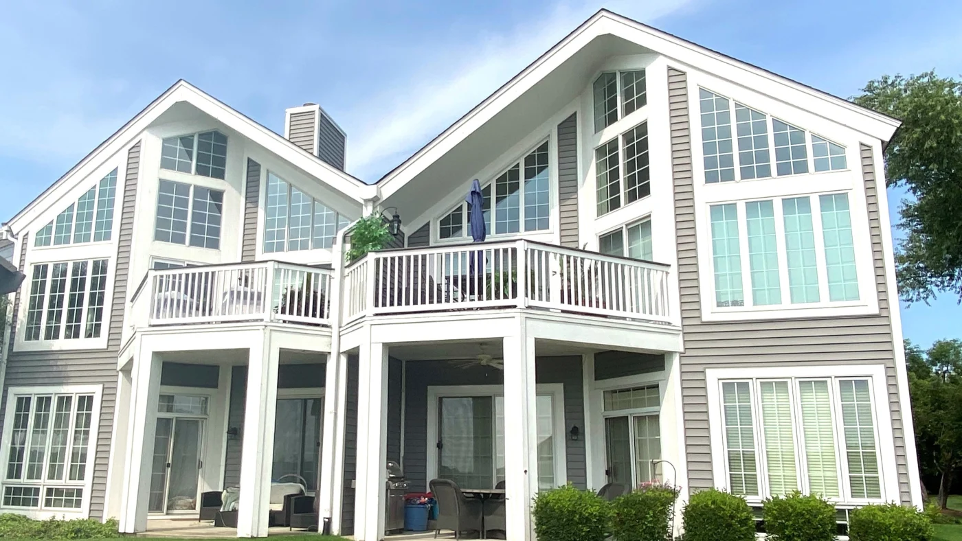 The front of a large house with many windows and a balcony in Wheaton, IL by Apex Exteriors.