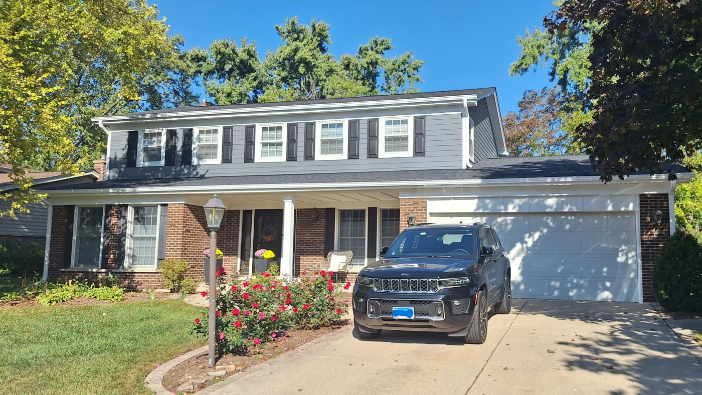 The front of a house with a gray roof and siding in Elmhurst, IL by Apex Exteriors.