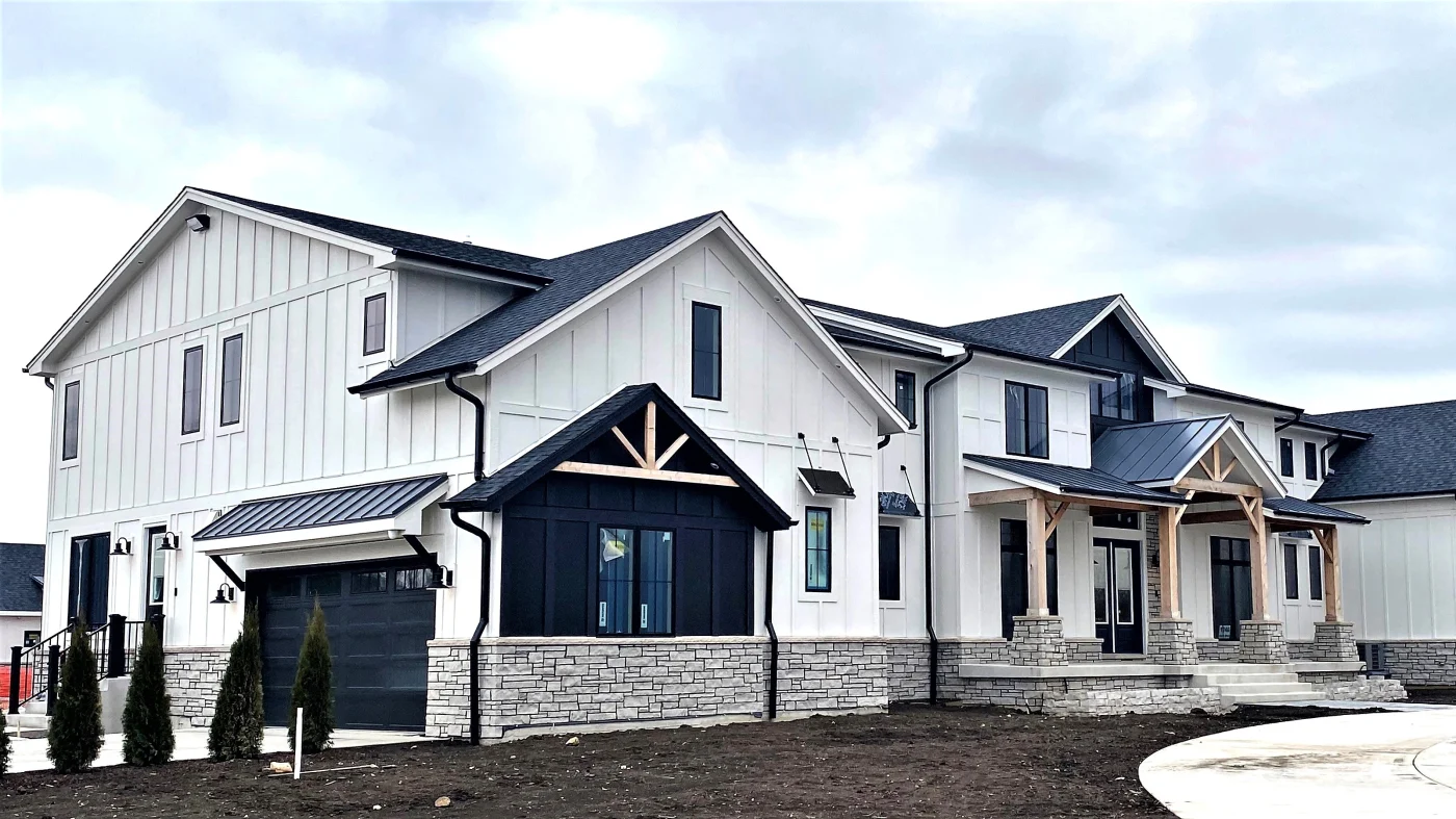 A large house with beautiful white siding and a black roof in Wheaton, IL by Apex Exteriors.