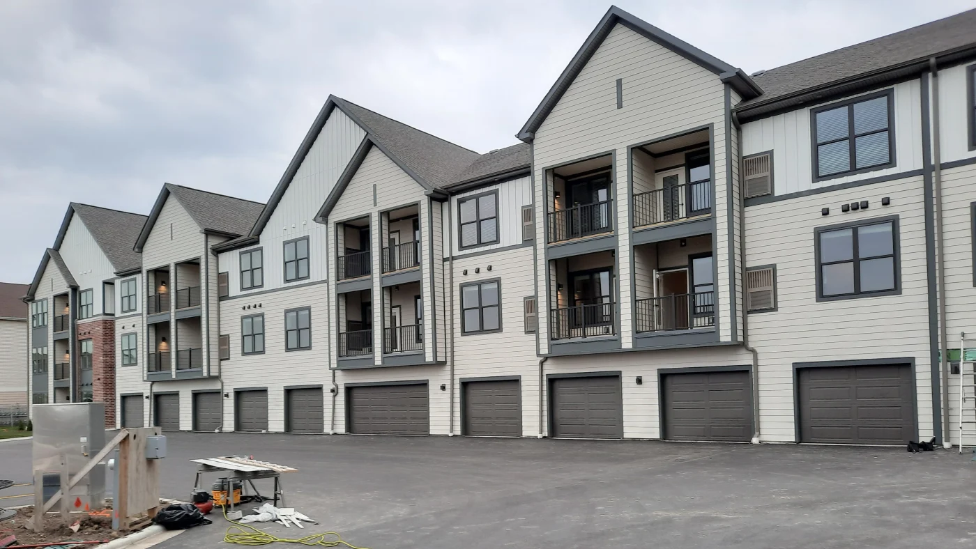 The side of an apartment complex with off-white siding and brown trim in Elk Grove Village, IL, by Apex Exteriors, Inc.