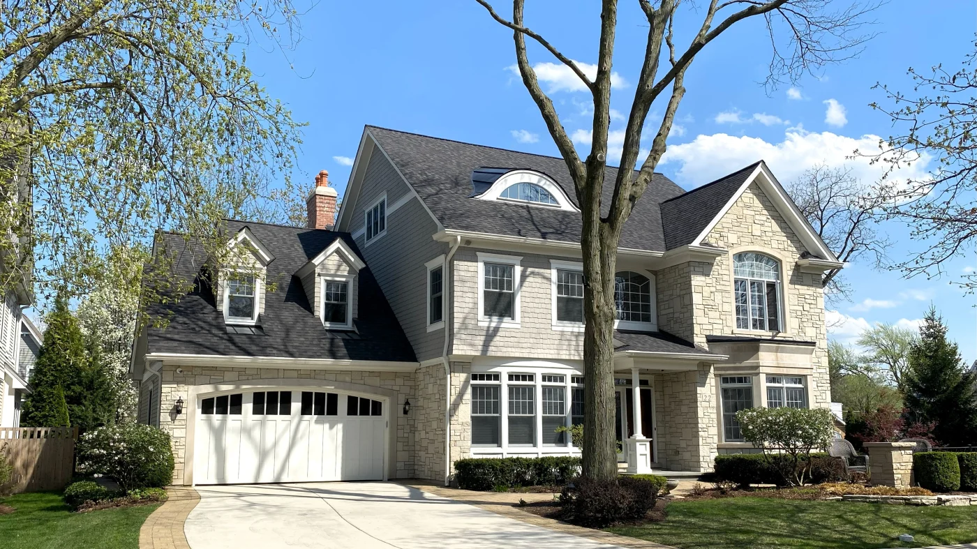 The front of a house with beige siding and a gray roof in Elmhurst, IL, by Apex Exteriors, Inc.
