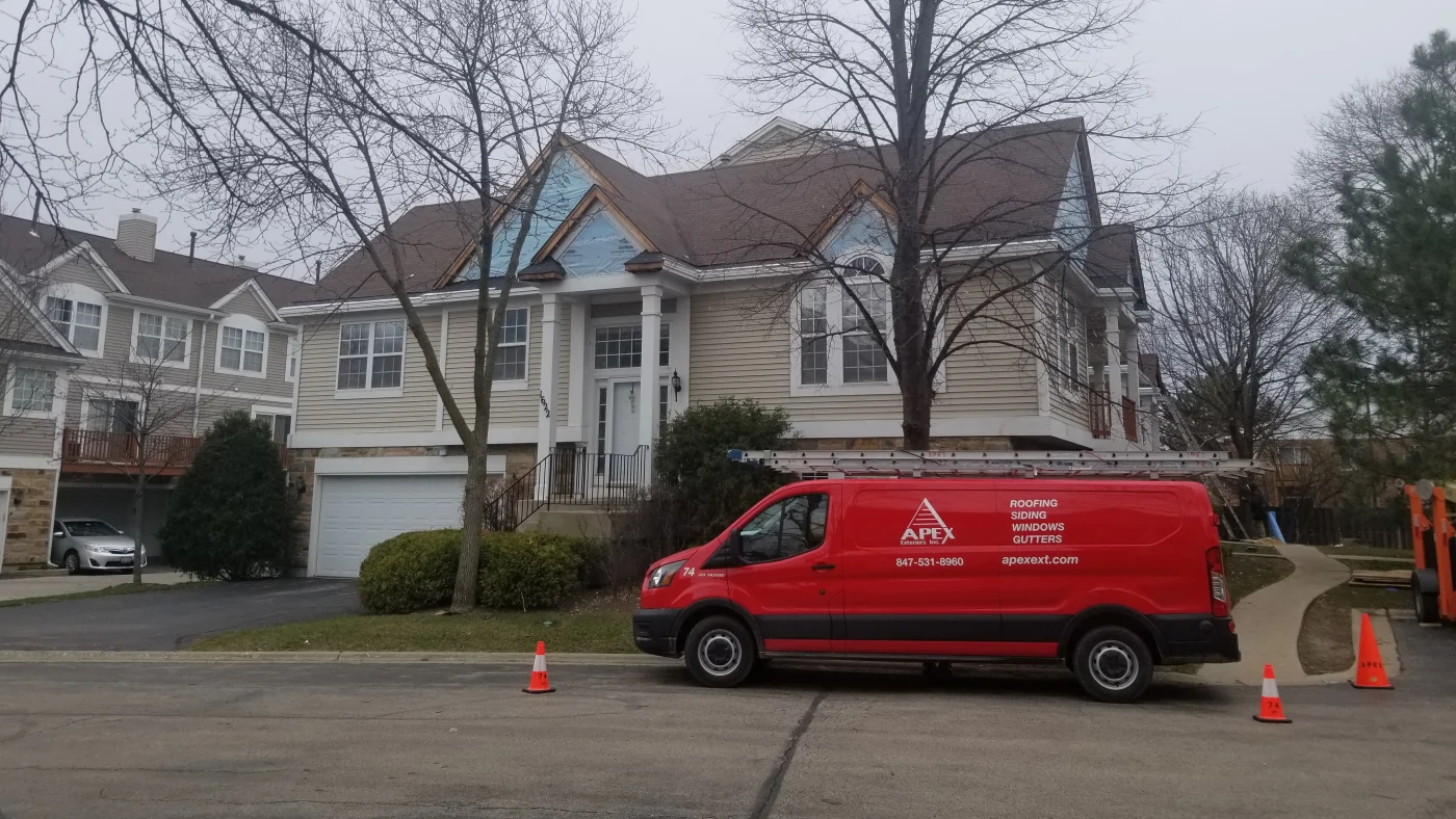 Exceptional Exterior Remodeling Services | Plainfield, IL | Apex Exteriors, Inc. A work van parked in front of a house with beige siding and a brown roof in Plainfield, IL, by Apex Exteriors, Inc.