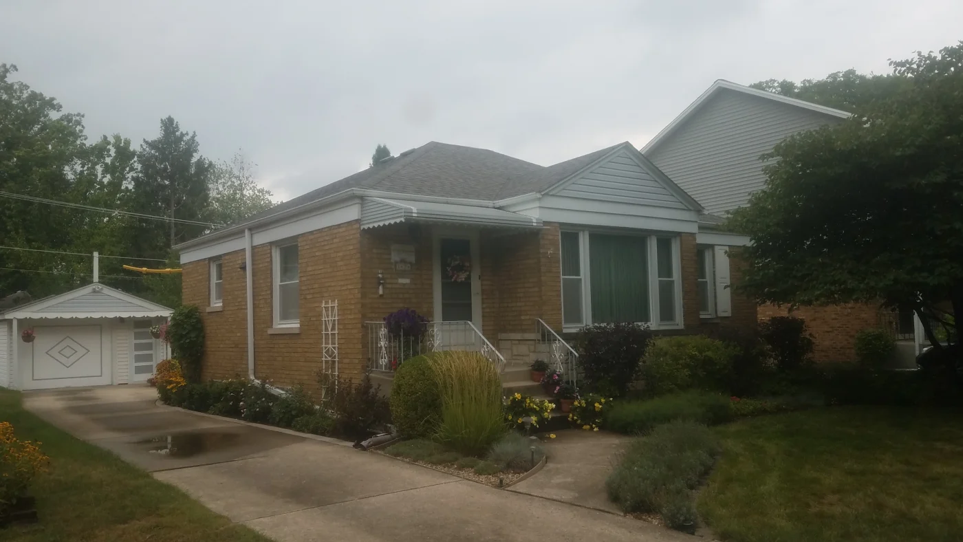 The front and side of a house with orange siding and a gray roof in LaGrange, IL, by Apex Exteriors, Inc.