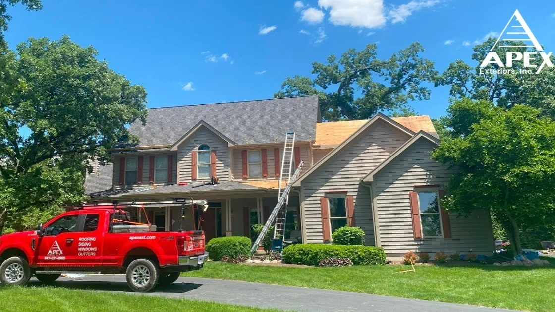A work truck is parked outside of a house with tan siding in Elk Grove Village, IL, by Apex Exteriors, Inc.