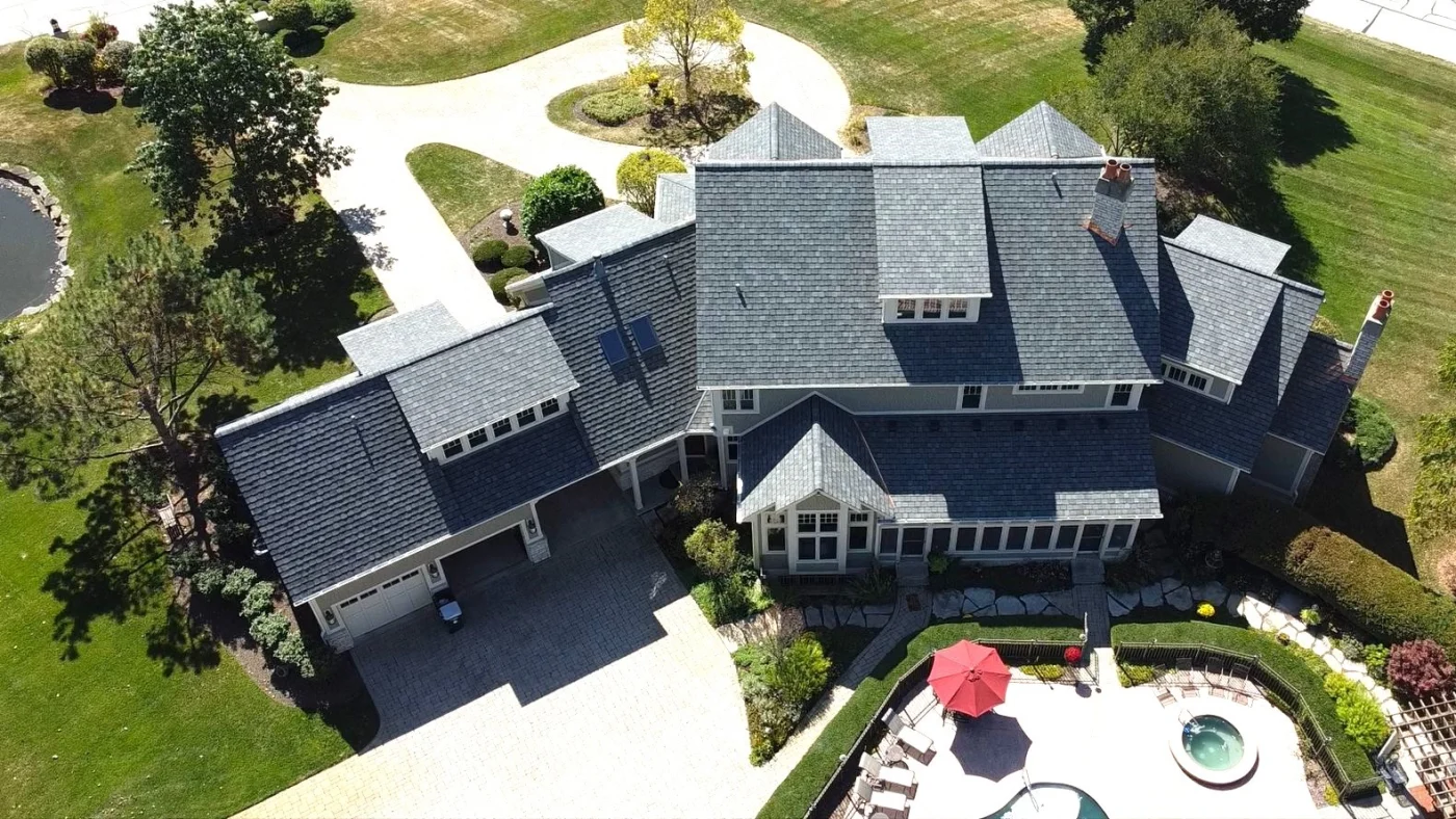 A sky view of a large house with gray siding and a gray roof in Wheaton, IL, by Apex Exteriors, Inc.