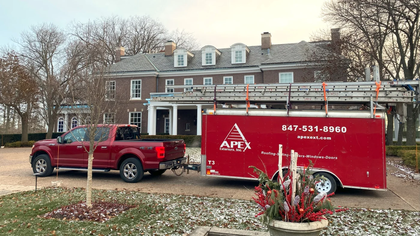 Remarkable Residential Roof Replacement | Plainfield, IL | Apex Exteriors, Inc. A work truck and trailer parked in front of a house in Plainfield, IL, by Apex Exteriors, Inc.