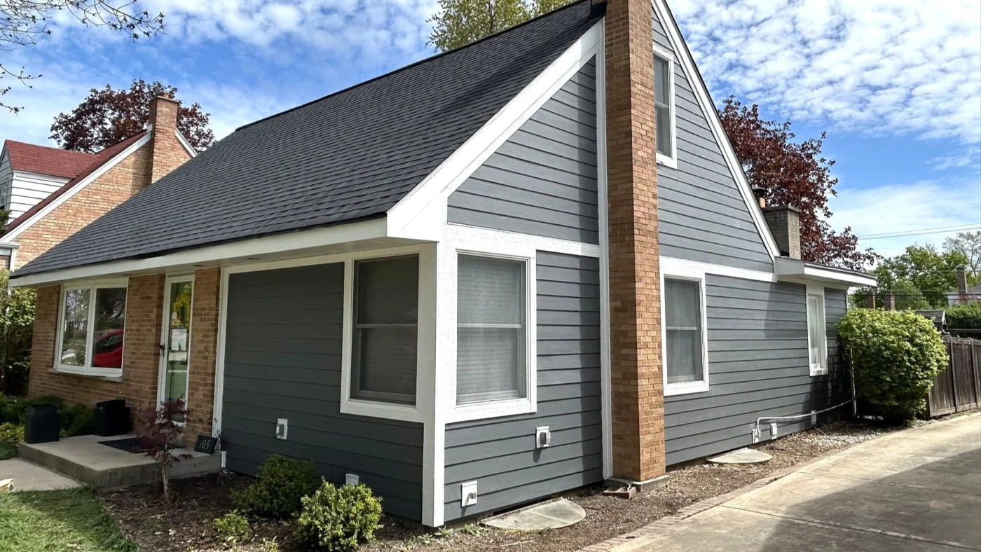 A small house with gray vinyl siding and red brick siding in Elk Grove Village, IL, by Apex Exteriors, Inc.