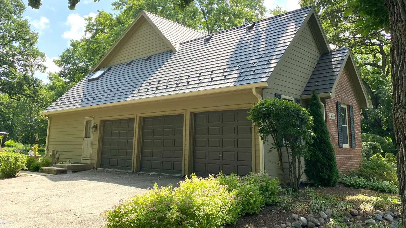 The side of a house with green siding and a three-car garage in LaGrange, IL, by Apex Exteriors, Inc.
