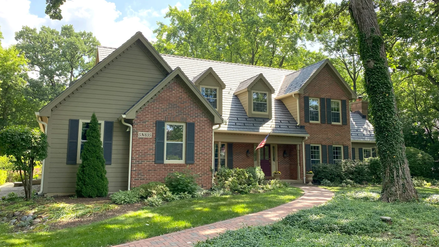 The front of a house with some red brick siding and some green vinyl siding in LaGrange, IL, by Apex Exteriors, Inc.