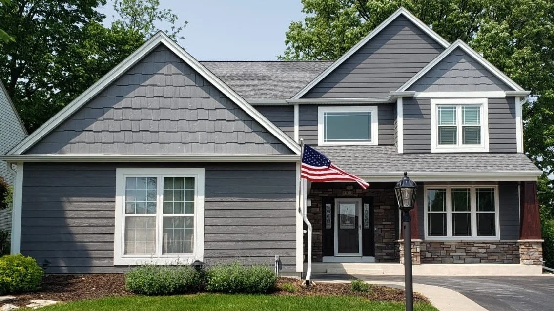 The front of a small house with gray siding and white trim in Elmhurst, IL, by Apex Exteriors, Inc.