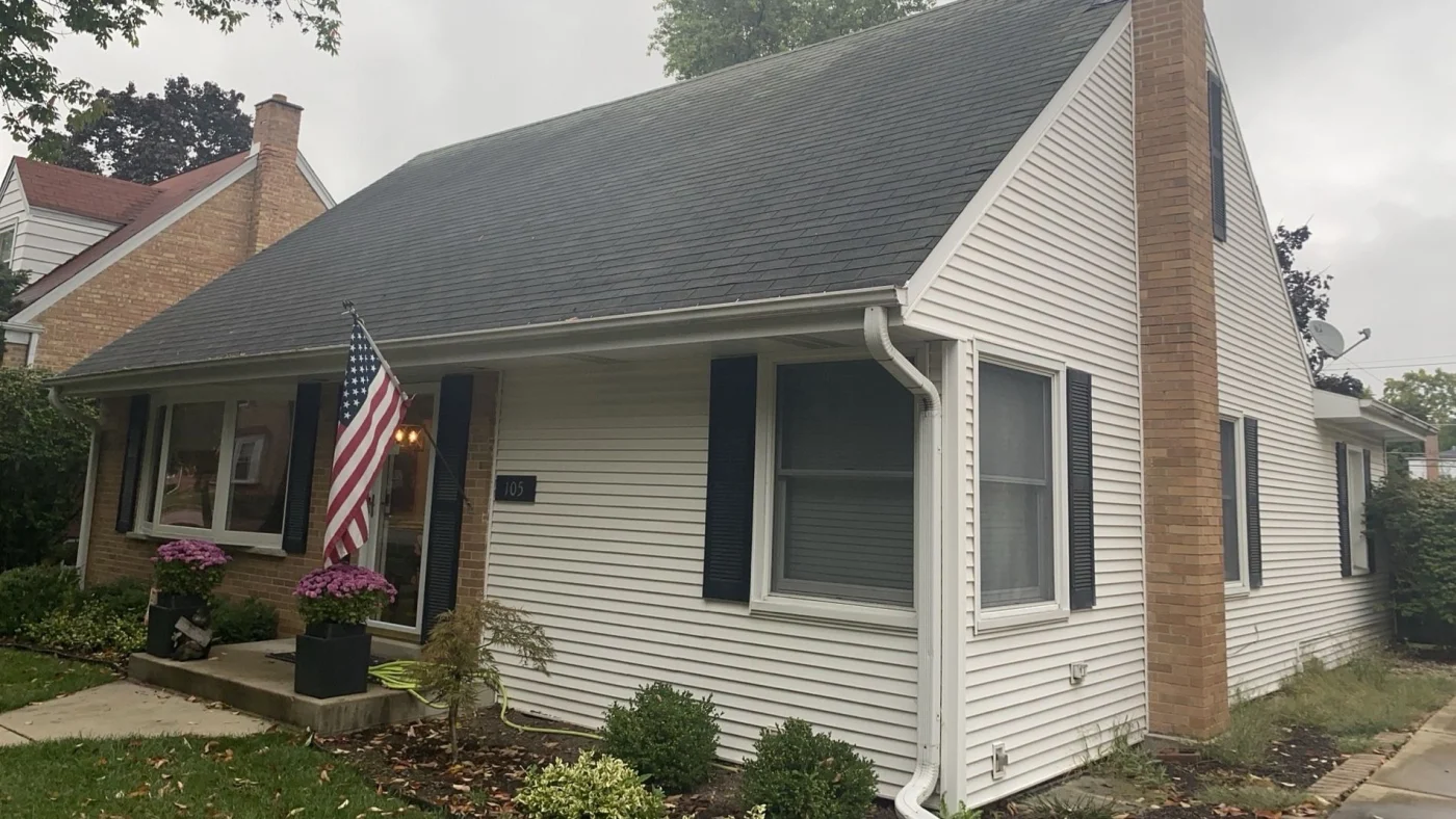The front of a small house with white siding and a gray roof in LaGrange, IL, by Apex Exteriors, Inc.