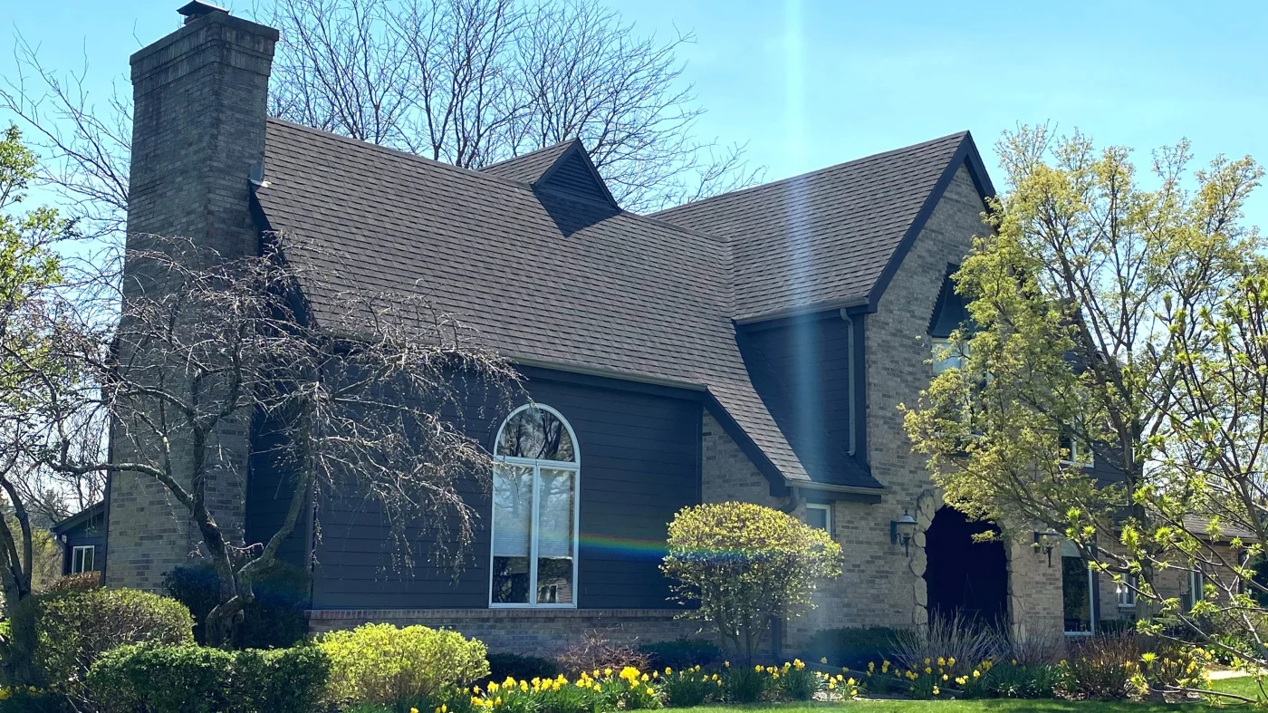 The front of a house with brown siding and a brown roof in Wheaton, IL, by Apex Exteriors, Inc.