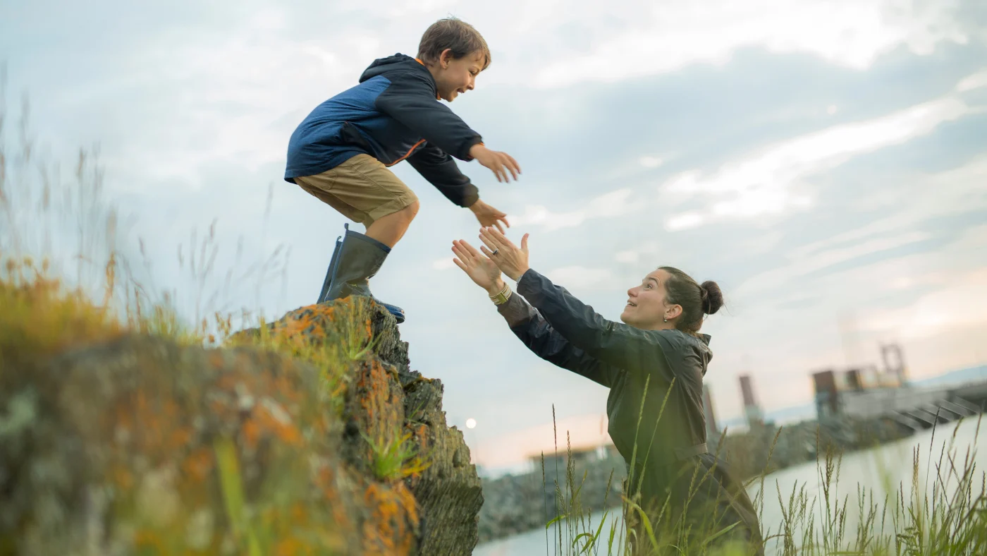 Trustworthy Exterior Home Remodeling Experts | Chicago, IL | Apex Exteriors, Inc. A mom holding out her arms to catch her son as he jumps off a small ledge in front of her.