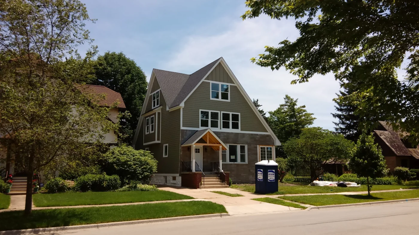 Looking across a street at a house with green siding in Northbrook, IL, by Apex Exteriors, Inc.