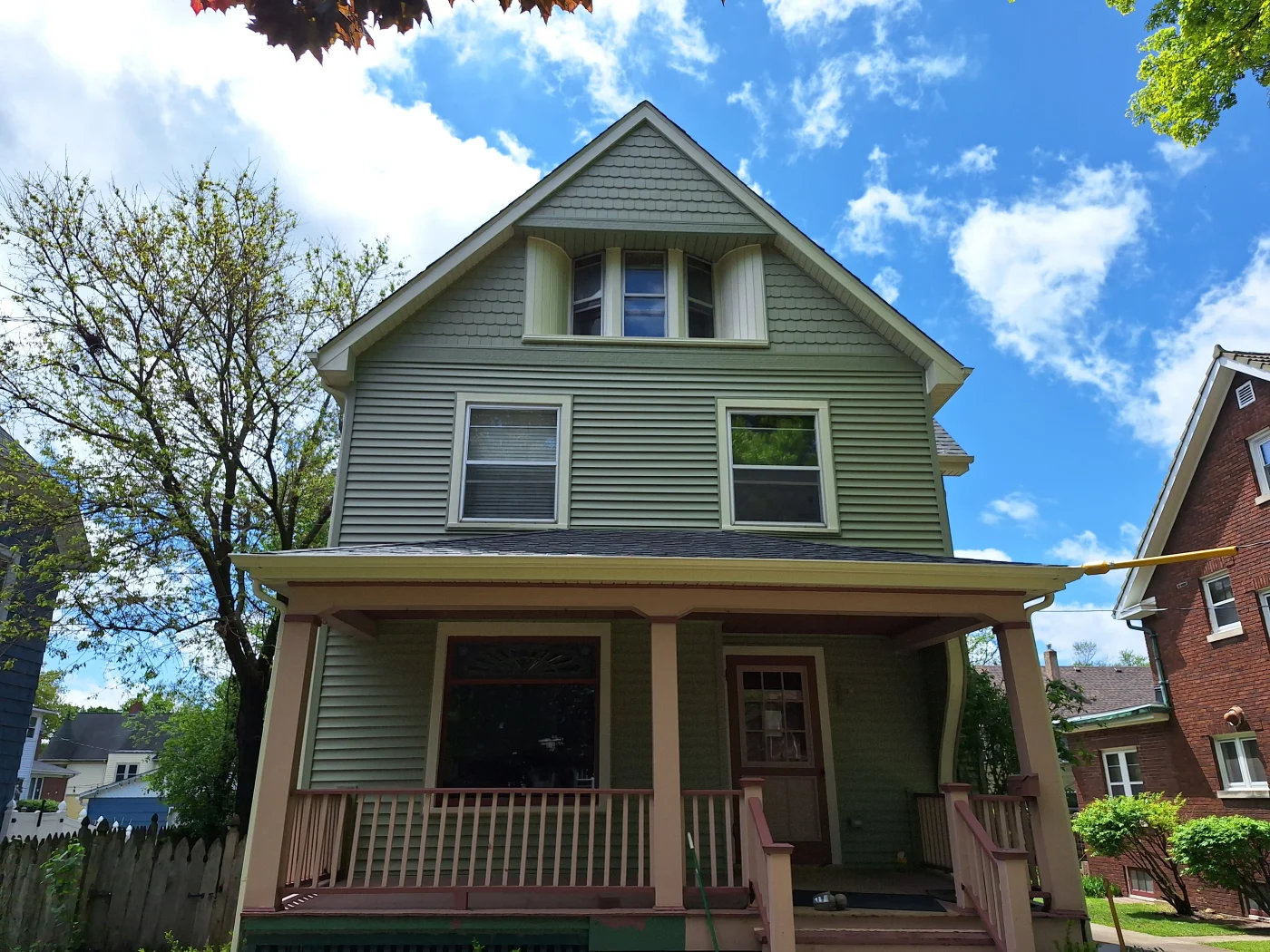 Flawless Window And Door Installation | Plainfield, IL | Apex Exteriors Two-story green home with horizontal siding, white-trimmed windows, gabled roof, and covered front porch.