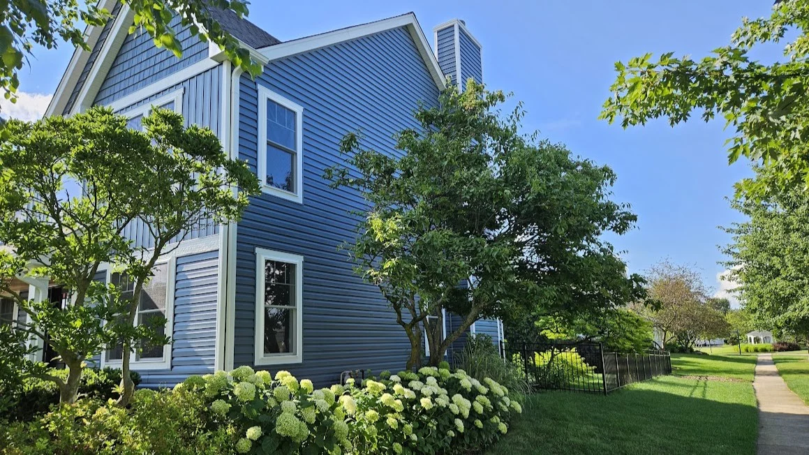 Outstanding Window Replacement | Glenview, IL | Apex Exteriors, Inc. The side of a house with blue siding and multiple gorgeous windows trimmed in white in Glenview, IL, by Apex Exteriors, Inc.