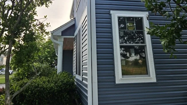 Stunning Replacement Windows | Glen Ellyn, IL | Apex Exteriors, Inc. The side of a house with blue siding and windows trimmed in white in Glen Ellyn, IL, by Apex Exteriors, Inc.