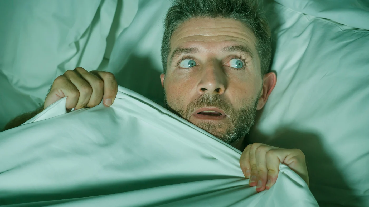 Caring Exterior Home Remodeling Experts | Chicago, IL | Apex Exteriors, Inc. A man in a bed, pulling up the covers in fear.