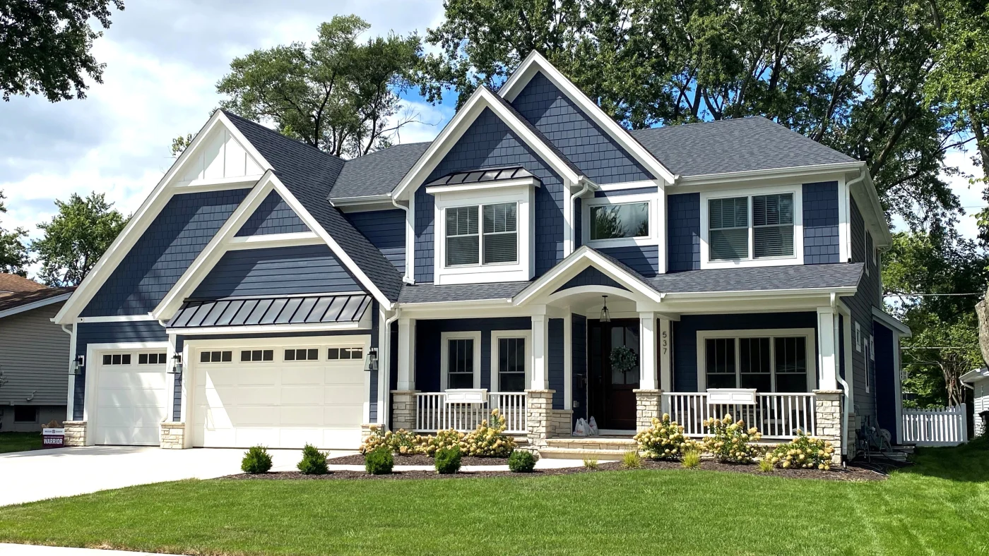 Outstanding Siding Installation | Elgin, IL | Apex Exteriors Inc. Two-story home with dark blue siding, gray shingle roof, white trim, and covered front porch with stone accents.