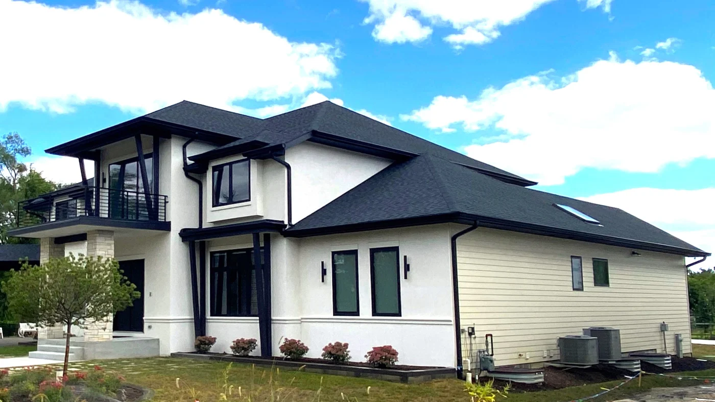 Remarkable Gutter Installation | Elgin, IL | Apex Exteriors Inc. Modern two-story home with white exterior, dark roof, and black trim, featuring a clean black gutter system and downspouts along the roofline.