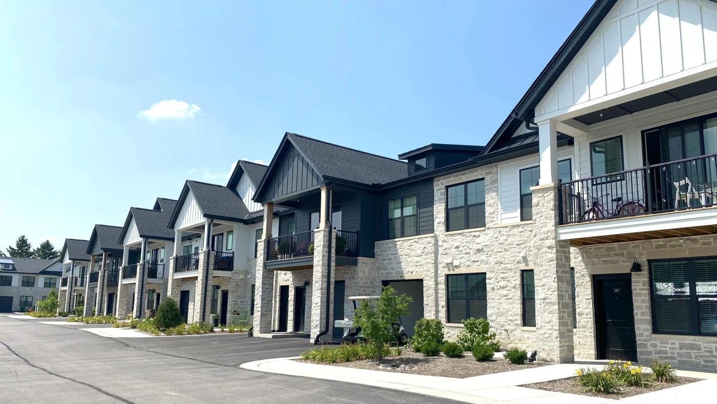 Remarkable Multi-Family Exterior | Elgin, IL | Apex Exteriors Inc. Multi-family residential buildings with stone exteriors, dark siding accents, and gabled roofs, featuring private balconies, covered entries, and a clean shared driveway.