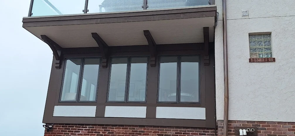 Reliable Window Installation | Bartlett, IL | Apex Exteriors, Inc. Cozy home and a row of tall, newly installed windows, creating a bright sunroom-style space that blends seamlessly with the existing exterior.